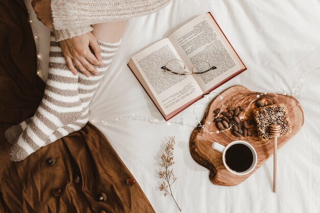 Crop lady sitting near book and healthy snacks