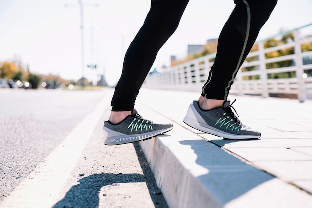 Crop legs exercising on sidewalk