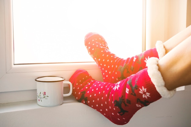 Crop legs and mug near window