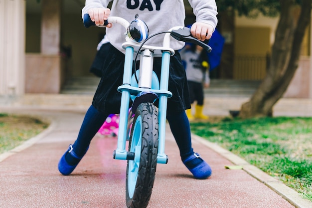 Crop little girl on bicycle