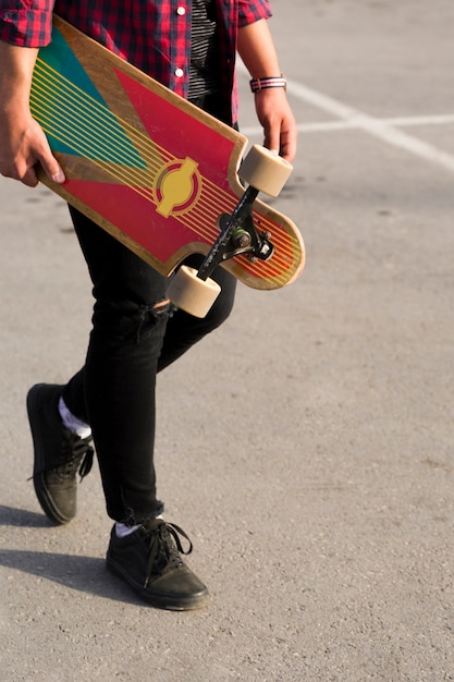 Foto gratuita ritaglia il longboard nelle mani dei pantaloni a vita bassa