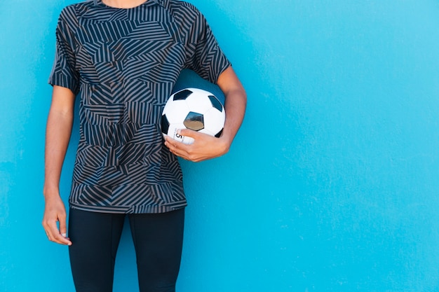 Crop male with football on blue backdrop 