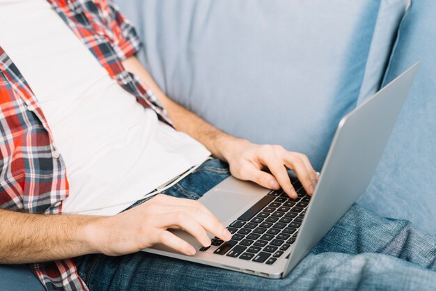 Crop man browsing laptop