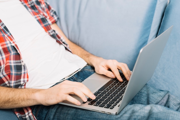 Crop man browsing laptop