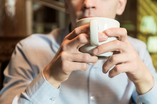 Crop man drinking hot beverage