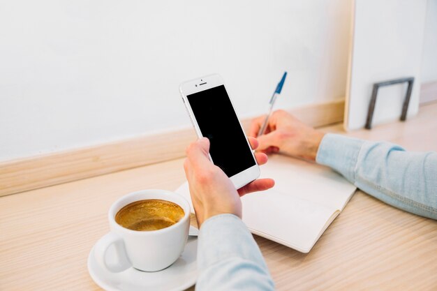 Crop man hands making notes from smartphone