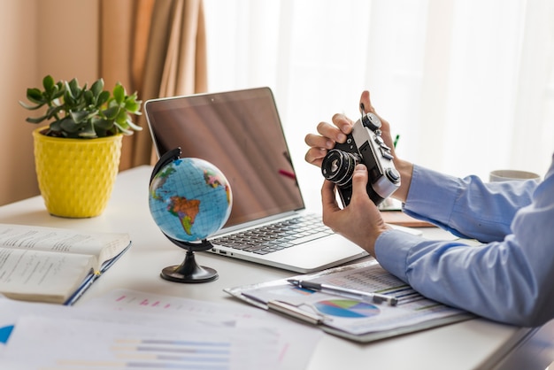 Crop man holding camera in office