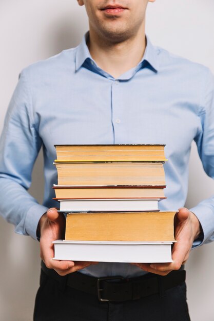 Crop man holding stack of books