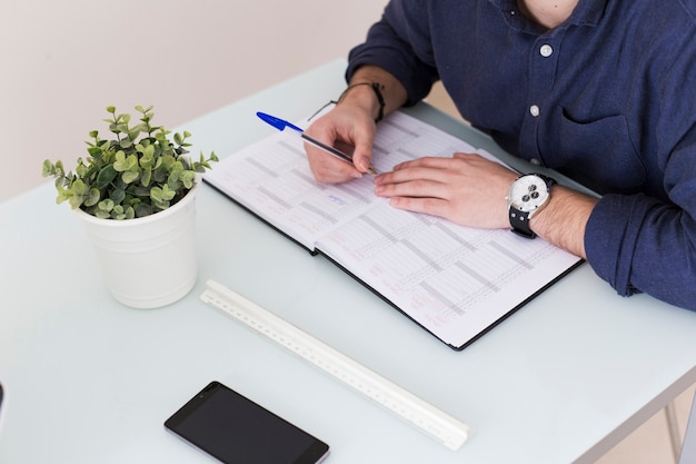 Crop man making notes in notebook