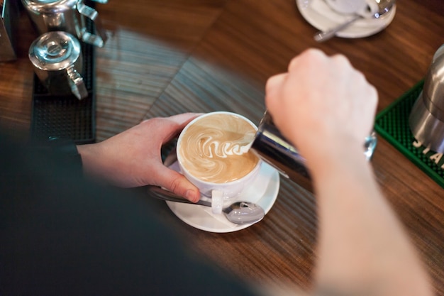 Crop man making tasty latte