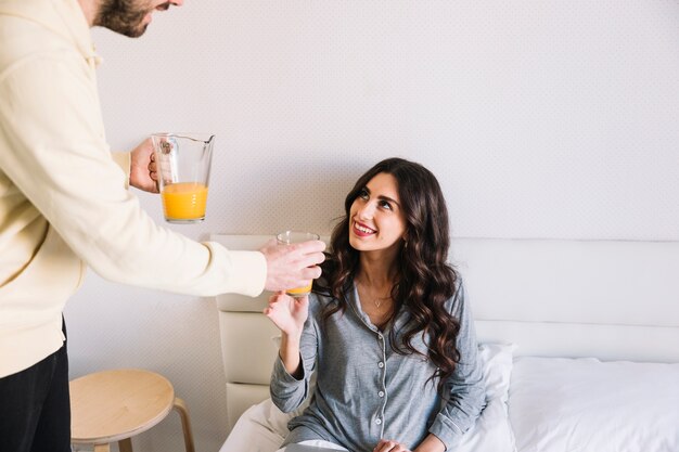 Crop man offering juice to woman