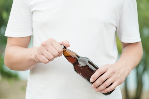 Crop man opening bottle of beer