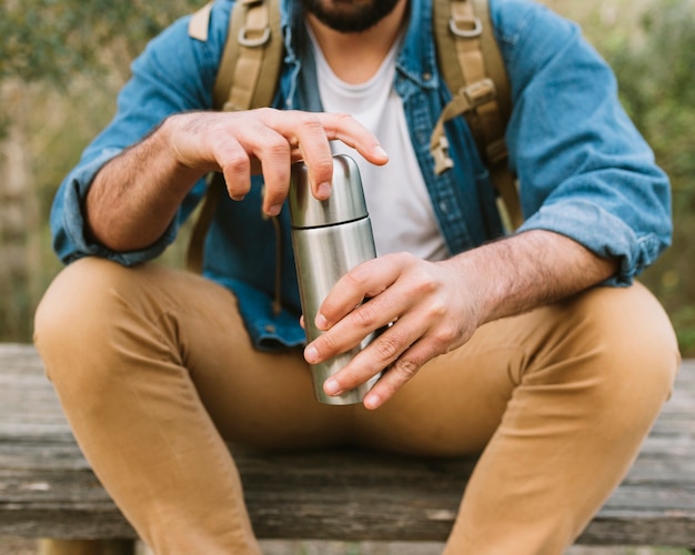 Crop man opening thermos