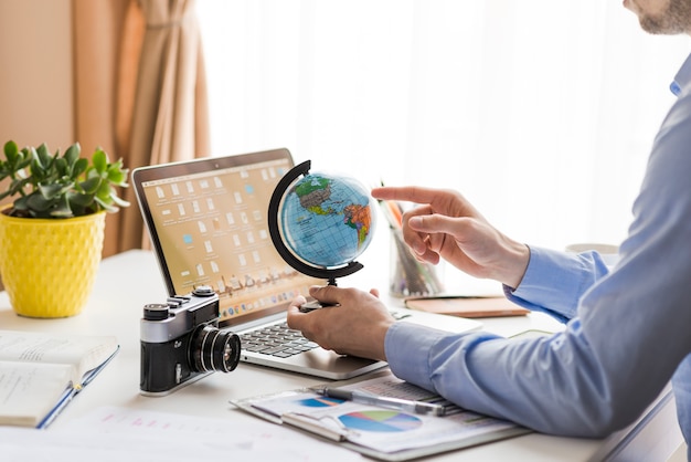 Free photo crop man pointing at globe in office