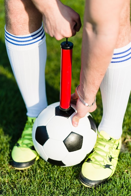 Free photo crop man pumping soccer ball