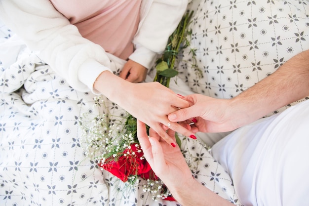 Crop man putting ring on girlfriend finger