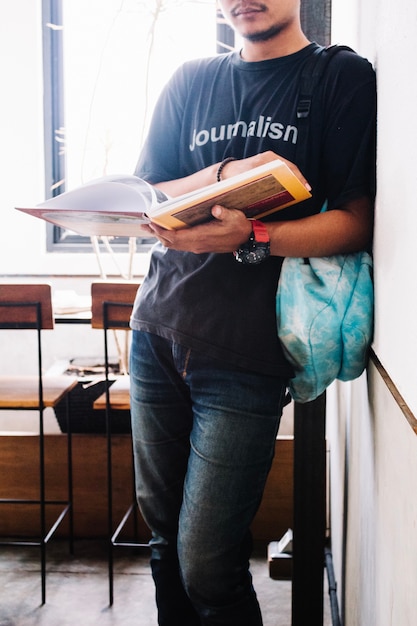 Free photo crop man reading book near wall