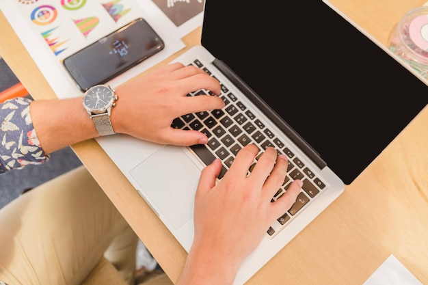 Crop man typing on laptop