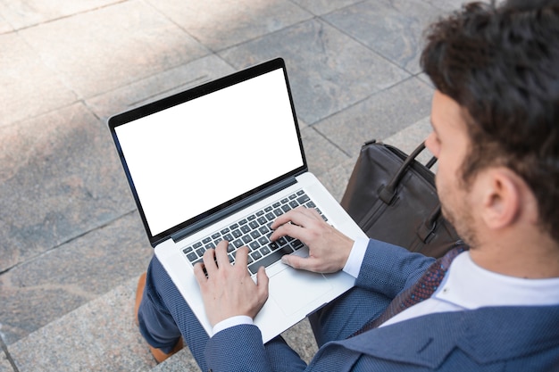 Crop man using laptop on stairs