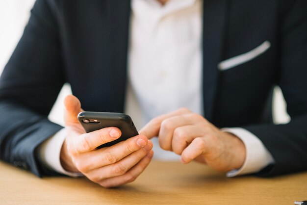 Crop man using phone in office