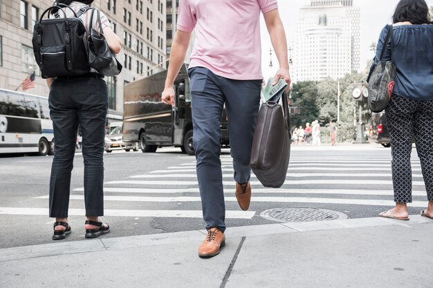 Crop man with bag crossing road