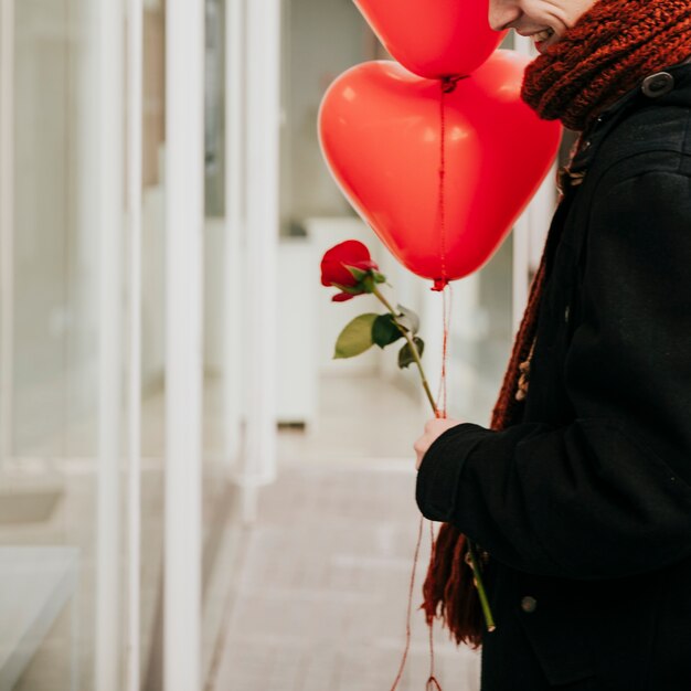 Crop man with balloons and flower