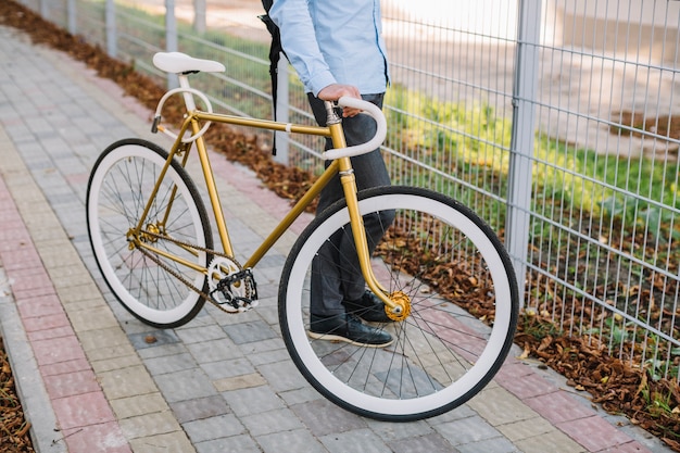 Crop man with bicycle near fence