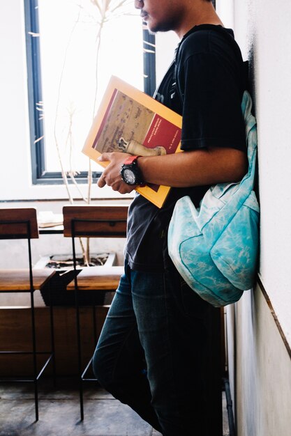 Crop man with book standing in classroom