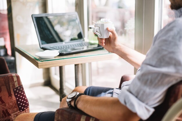 Crop man with coffee cup in cafe