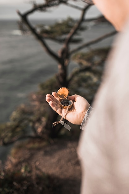 Crop man with compass on cliff