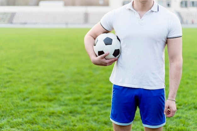 Crop man with soccer ball on stadium