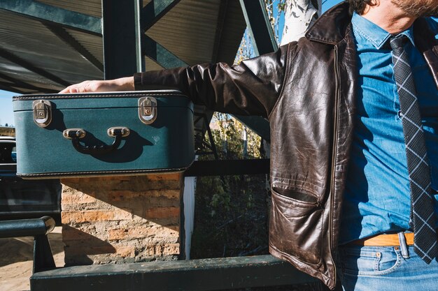 Crop man with suitcase on station