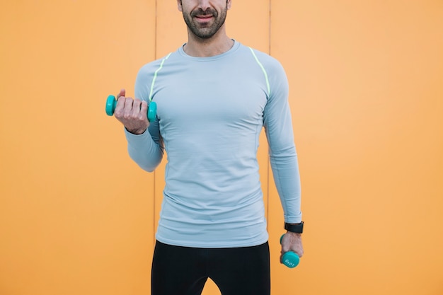 Crop man working out with dumbbells