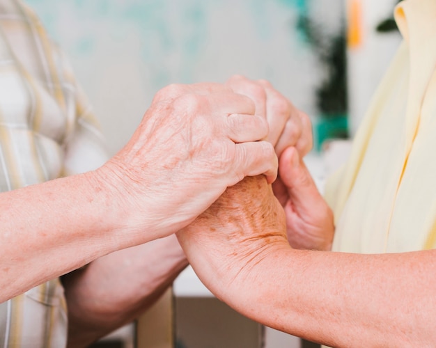 Crop mature couple holding hands