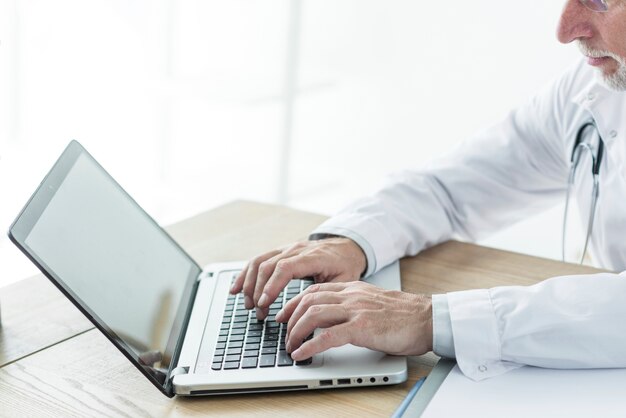 Crop medical practitioner using laptop