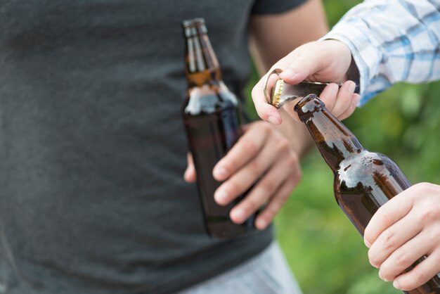 自然の中でビールを開ける作物の男性