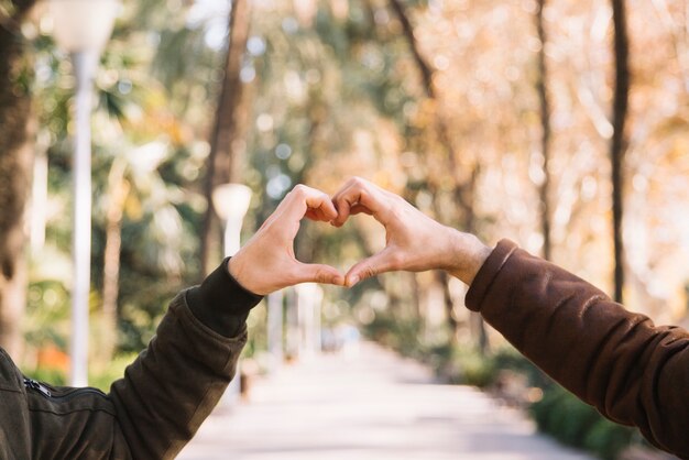 Crop men stacking hands showing heart