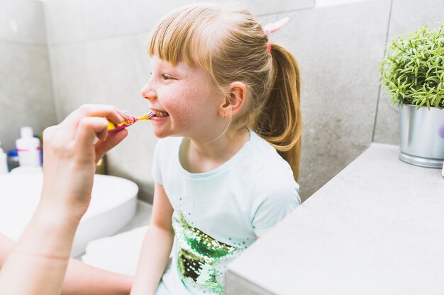 Crop mother brushing teeth of daughter