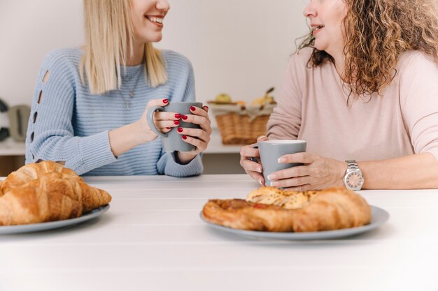 Crop mother and daughter having breakfast