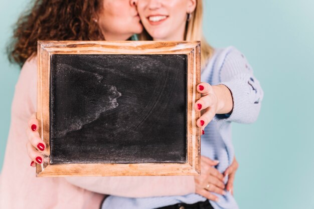 Crop mother and daughter holding blackboard