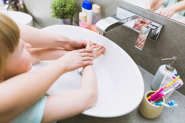 Crop mother helping daughter in bathroom