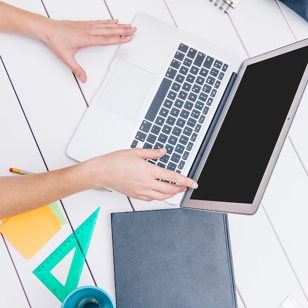 Crop office worker with laptop at table