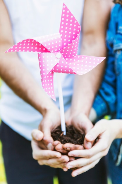 Crop people holding dirt and paper windmill