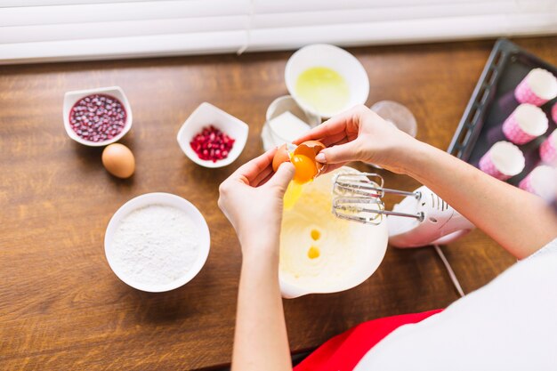 Crop person adding eggs to batter