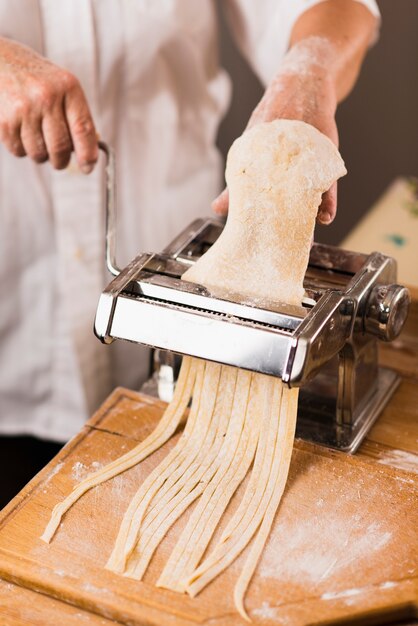 Crop person cutting dough for pasta