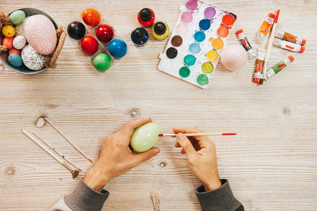 Crop person decorating eggs for holiday