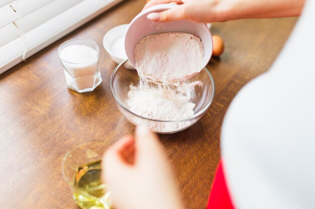 Crop person filling bowl with flour