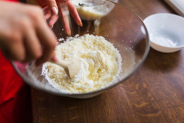 Crop person mixing batter with wooden spoon