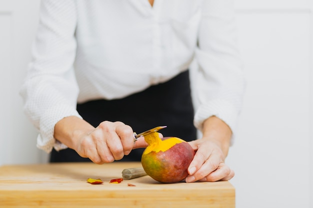 Crop person peeling fruit