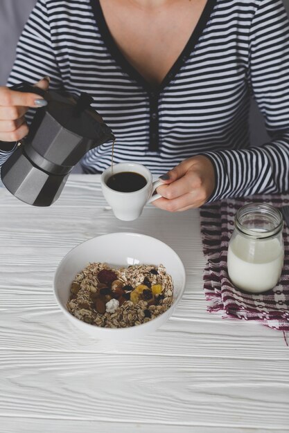 Crop person pouring coffee for breakfast